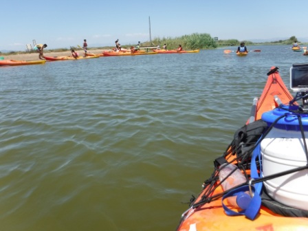 Un grupo de kayakistas organizándose en la orilla de un canal, listos para una jornada de remo en el Delta del Ebro, España