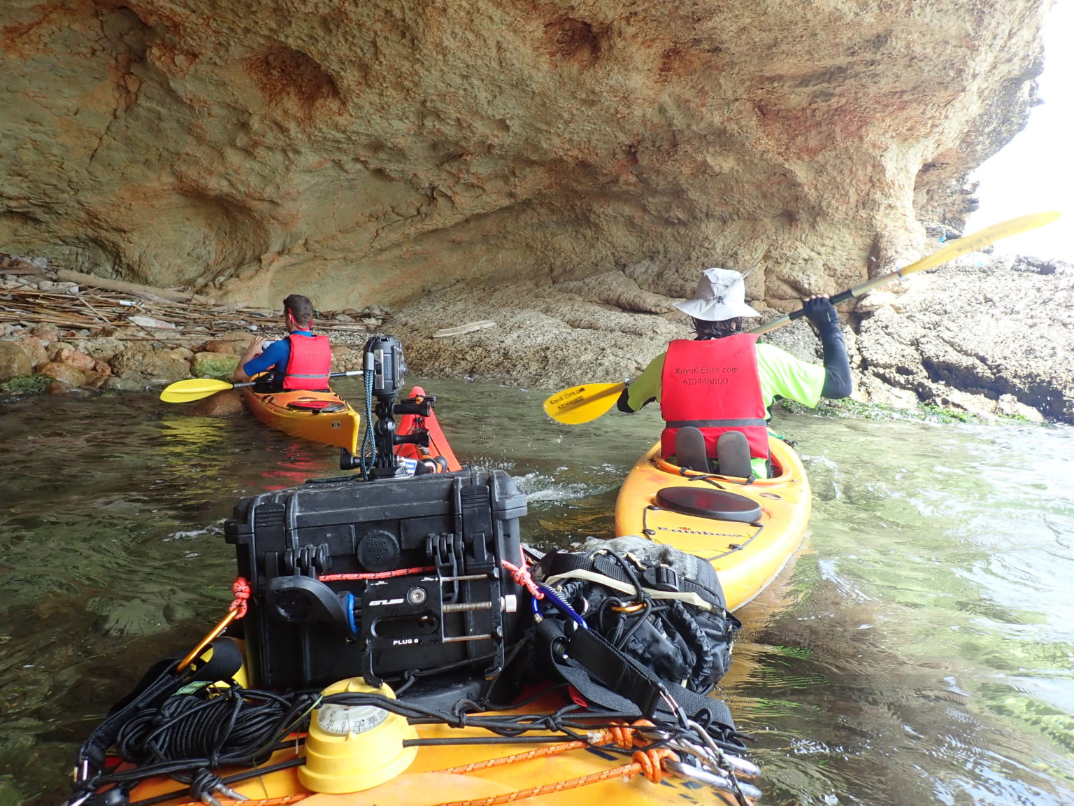 Dos kayaks navegando cerca de una formación rocosa costera.