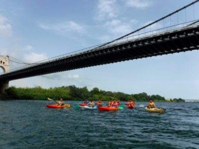 Un grupo de kayaks explorando un río bajo un gran puente.