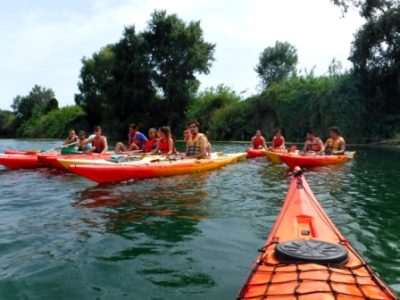 Jóvenes y adultos se reúnen en sus kayaks para un descanso o una charla en las aguas del río Ebro.