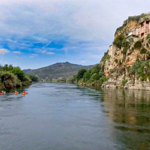 Un grupo disfruta de una travesía en kayak por el río Ebro, pasando por el impresionante paisaje de Miravet, Tarragona.