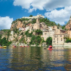 El majestuoso Castillo de Miravet dominando el paisaje del río Ebro y el pueblo, en un día parcialmente nublado.