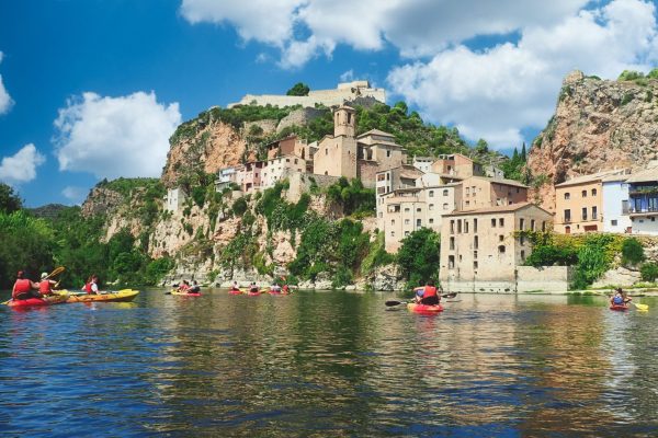 El majestuoso Castillo de Miravet dominando el paisaje del río Ebro y el pueblo, en un día parcialmente nublado.
